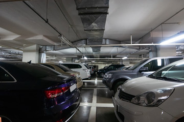 Illuminated underground car parking interior under modern mall with lots of vehicles