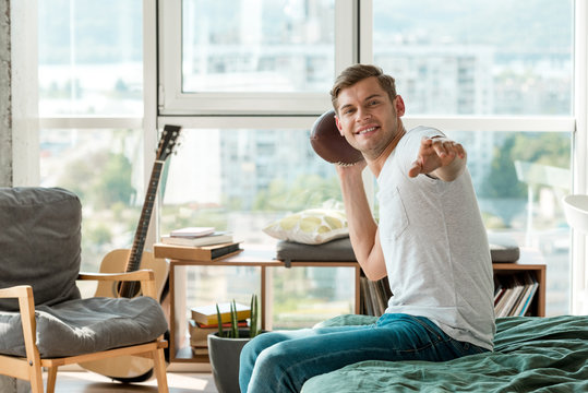 Smiling Man Throwing Rugby Ball In Hand At Home