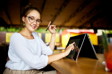 Digital artist finger touches convertible to 2 in 1 laptop display in tent mode and holds stylus....