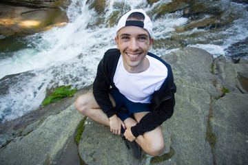 Young man walk near fast river in middle of forest