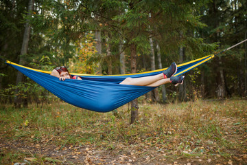 Photo of young brunette lying in hammock in woods during day