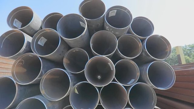 View through metal pipes of large diameter. Metal pipes of large diameter in a metal warehouse, large pipes in an open-air warehouse, large diameter pipes stacked in rows