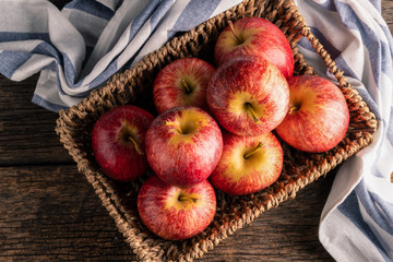 Fresh apples in basket on wood table