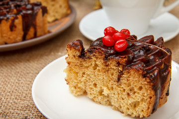 Chocolate cake decorated with bunch of viburnum and cup of coffee.