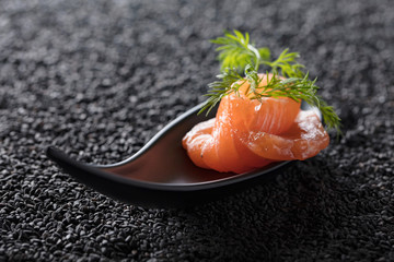 Salted salmon with dill on the background of black sesame.