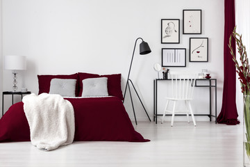 Contrast colors, white, burgundy and black in a modern bedroom interior with bed, dressing table,...