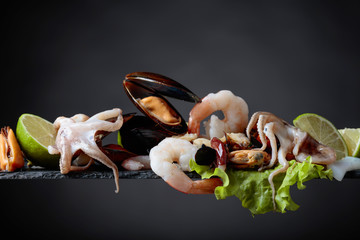 Mixed delicious seafood with salad and lime slices .