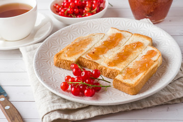 Healthy Breakfast with toast, jam and red currants, a Cup of coffee on the white table.