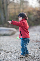 Fototapeta premium Little boy playing on gravel bank pointing finger