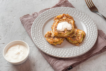 Fried zucchini slices in egg batter with garlic on a plate.