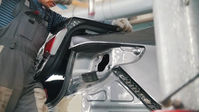 Mechanic man repairs the car body with a hammer in a car repair shop