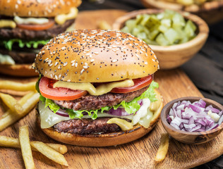 Hamburgers and French fries on the wooden tray.