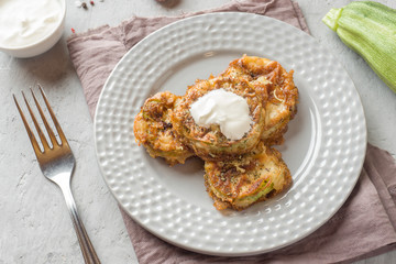 Fried zucchini slices in egg batter with garlic on a plate.