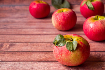 Fresh red apples with green leaves on a Dark wooden background.
