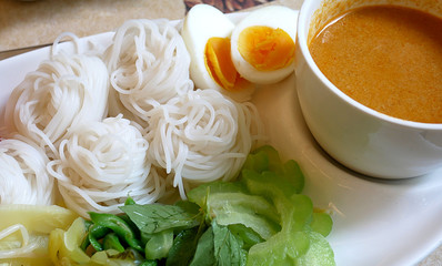 Rice noodles in fish curry sauce with vegetables.Delicious thai food serving with boiled egg.