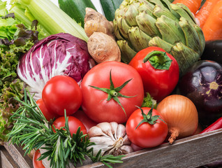 Fresh multi-colored vegetables in wooden crate.