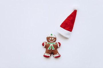 Christmas gingerbread in the form of a small ginger man and next to him a red traditional hat. Christmas or New Year's concept in a minimal style.