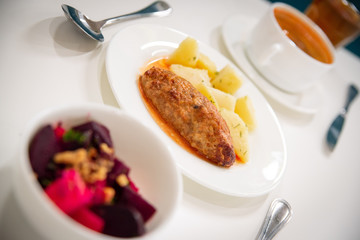 Soup, salad and a hot dish stand in a line on a white table. Суп, салат и горячее блюдо стоят в линию на белом столе.