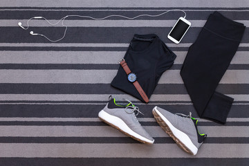 Top view of running shoes, womens clothes, pants tights, smartphone run application isolated on grey carpet. - obrazy, fototapety, plakaty