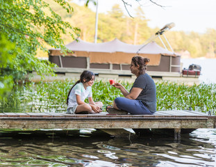 A woman holding a piece of watermelon is talking to her young daughter