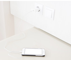 Fototapeta premium charging smartphone, cellphone on wooden table, blank screen mobile phone. Selective focus.Copy space, blank, mock up,top view