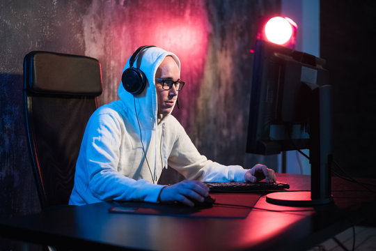 male hooded gamer playing online game on pc computer