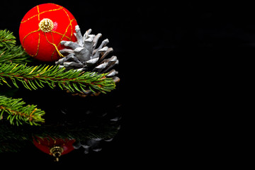 Christmas corner,  focus on the painted spruce cone, decorations on black shiny surface, space for text.