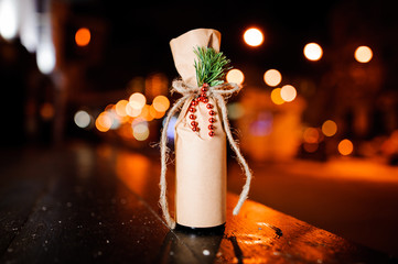 Adorable christmas decorated bottle with ribbon, fir-tree branch and beads in the craft paper - Powered by Adobe
