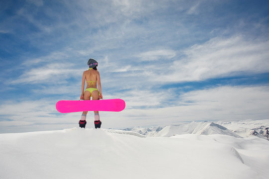 Rear view of young girl with a snowboard on the background of clear sky