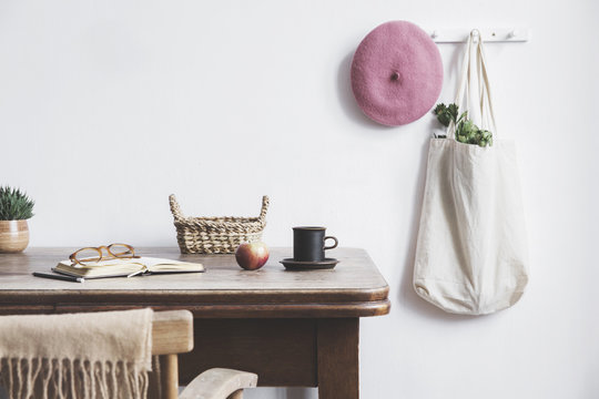 Vintage kitchen interior with mock up photo frame, cup of coffee, pink hat, white bag and box. Minimalistic concept of kitchen space.