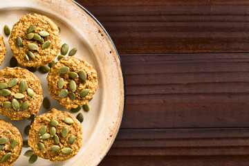 Frische hausgemachte gebackene Kürbis, Walnuss und Haferflocken Muffins mit Kürbiskernen bestreut, fotografiert mit Textfreiraum an der Seite (Selektiver Fokus, Fokus auf die Oberfläche der Muffins)