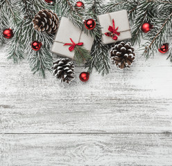 View from above, top, on a white wooden board, square background with evergreen, fir branch with pines, gift, present boxes and red tree globes with space for text, greeting card