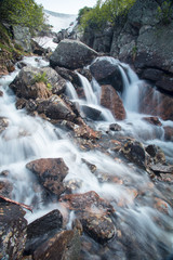 Великолепный горный пейзаж с водопадом. Красивый горный ручей и волшебные горные цветы