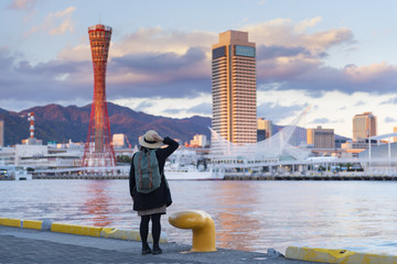 Tourist woman is enjoy watching beautiful view landmark of Kobe port at dusk.