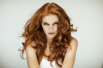 Naklejka premium Portrait of a beautiful young woman with long red curly hair and freckles, perfect make up