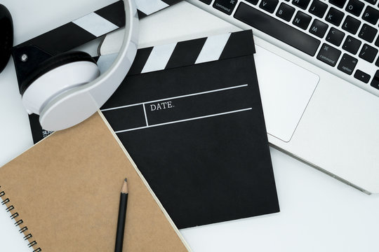 Movie maker with movie editing device,laptop, earphone, movie clapper board, note pad on white background.