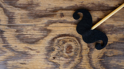 Top or flat lay view of Photo booth props a black mustache shape on a wooden background flat lay. Birthday parties and weddings.