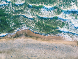 Aerial view of ocean waves crashing on beach.