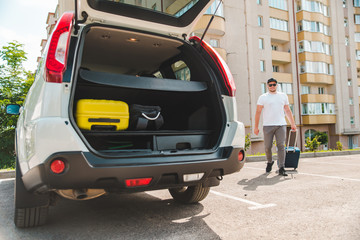 Naklejka premium man putting bags in car trunk. ready for car travel