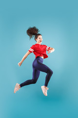 I am happy. Mid-air shot of pretty smiling young woman jumping and gesturing against pink studio background. Runnin girl in motion or movement. Human emotions and facial expressions concept