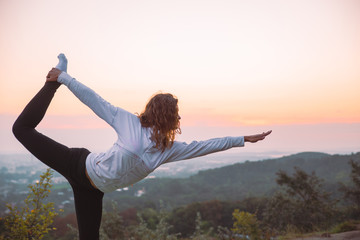 woman do yoga exercises at top of the hill on sunrise