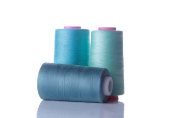 A bobbin with threads in blue tones on a white isolated background. accessories for sewing