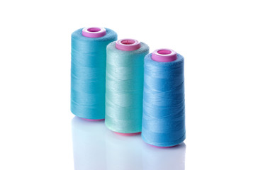 A bobbin with threads in blue tones on a white isolated background. accessories for sewing
