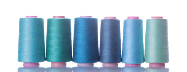 A bobbin with threads in blue tones on a white isolated background. accessories for sewing