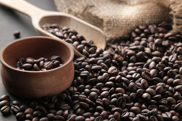 Fried coffee beans and a wooden spoon and a bowl on a black background.