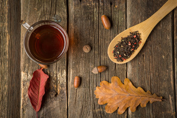Cup of tea with autumn leaves on wooden background