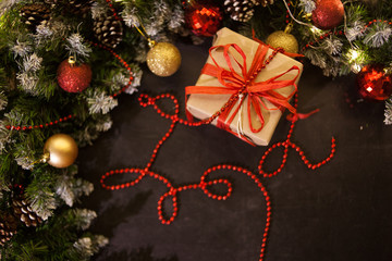 Christmas holiday background. Gifts with a red ribbon, Santa's cap and decor under a Christmas tree on a wooden board. 