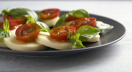 Caprese salad with ripe tomatoes and mozzarella with fresh Basil leaves. Italian food.