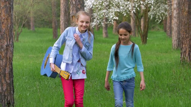 Attractive little Teen girlfriend walk in Park, two teenage female friends having fun and smiling. blonde and brown hair girls.
