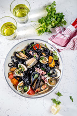 Homemade seafood Black pasta spaghetti with clams mussels octopus vongole in pan with white wine on marbled background